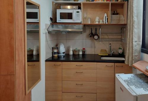una pequeña cocina con armarios de madera y microondas en Spring apartment Bahar nissim Jerusalem, en Jerusalén