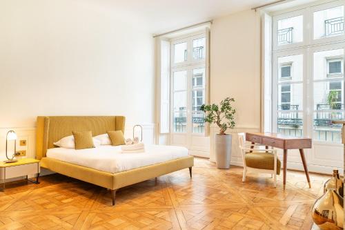 ein Schlafzimmer mit einem Bett, einem Schreibtisch und Fenstern in der Unterkunft Le Crébillon - Splendide appartement de 204m2 in Nantes