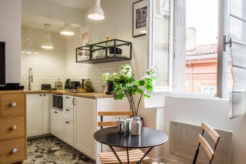 une cuisine avec une table et une plante. dans l'établissement Le Petit Capitole - Studio rénové à 2 pas du Capitole, à Toulouse