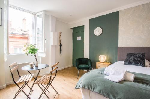 une chambre avec un lit, une table et des chaises dans l'établissement Le Petit Capitole - Studio rénové à 2 pas du Capitole, à Toulouse