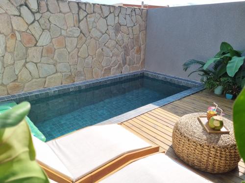 a swimming pool with a table and a stone wall at Kanui Milagres 112 in São Miguel dos Milagres