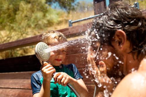 a young boy is playing with a water hose at ROBINSON QUINTA DA RIA - All Inclusive in Vila Nova de Cacela