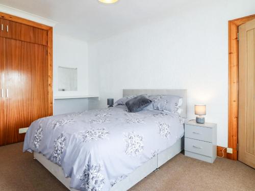 a bedroom with a white bed and a wooden cabinet at Rowan Cottage in Arbroath