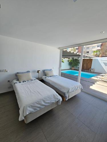 two beds in a room with a view of a pool at Nosotros Luxury Villa in Los Cristianos