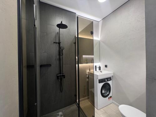 een badkamer met een douche en een wasmachine bij Апартаменты SMART №4 in Pavlodar