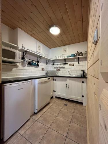 a kitchen with white appliances and a wooden ceiling at Zakodomki Domek Szałas in Kościelisko