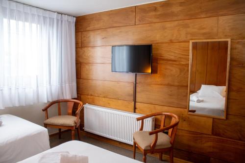 um quarto de hotel com duas camas e uma televisão de ecrã plano em Hotel Germania em Puerto Varas