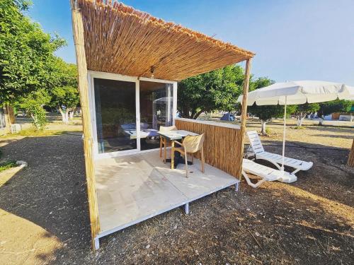 een klein gebouw met een tafel en stoelen en een paraplu bij ORANGE BEACH CAMP in Beldibi