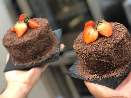 a person holding up two chocolate cakes with strawberries on them at Golden Lisbon Hotel in Lisbon