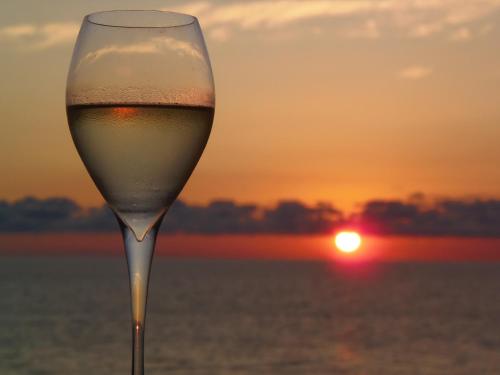 een glas wijn met de zonsondergang op de achtergrond bij Hotel Tramonto in Chakvi