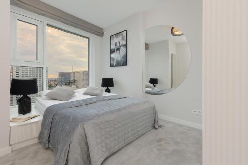 a white bedroom with a large bed and a mirror at Luxurious Unique Tower Apartment with City Skyline by Renters Prestige in Warsaw