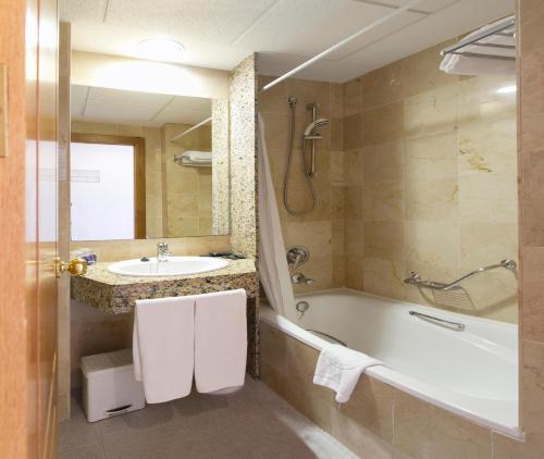 a bathroom with a bath tub and a sink at Hotel Poseidon Playa in Benidorm