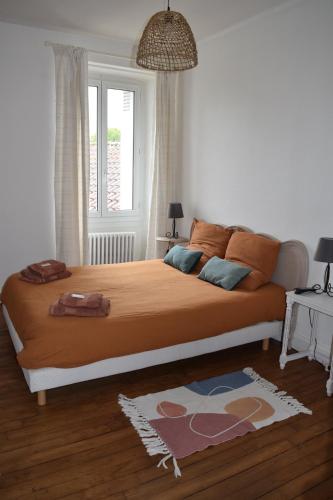 a bedroom with a large bed with orange sheets and a window at Logis de Fornel in La Rochefoucauld