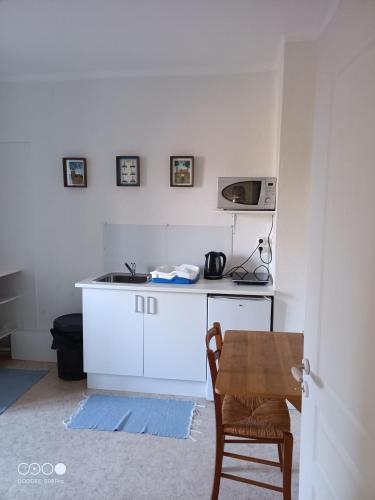 a white kitchen with a table and a microwave at Logis de Fornel in La Rochefoucauld