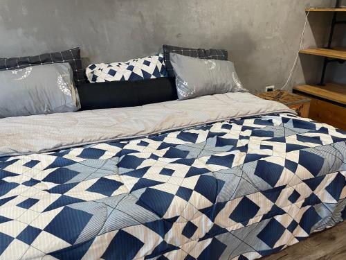 a bed with a blue and white quilt on it at 420 Canopy Studio Meals Included in Chiang Mai