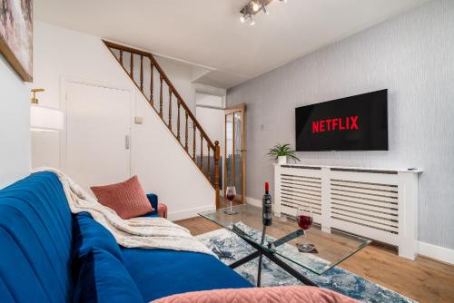 ein Wohnzimmer mit einem blauen Sofa und einem Fernseher in der Unterkunft Watford Casa - 2 bed and 2 bath home near Watford Junction Station in Watford