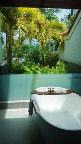 a bathroom with a white sink and a palm tree at Taj Wayanad Resort & Spa, Kerala in Wayanad