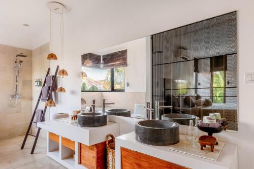 uma casa de banho com 3 lavatórios e um espelho grande em Villa Plumeria - Walk to Bingin Beach em Uluwatu