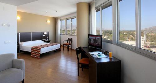 Una habitación de hotel con una cama y un escritorio con televisión. en La Estación, en Benidorm