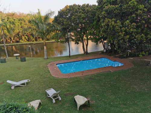 ein Pool im Gras mit zwei Liegestühlen in der Unterkunft Tortuga 22 - Caribbean Estates in Port Edward
