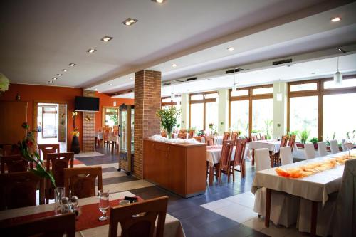 a restaurant with white tables and chairs and windows at Motel Skalka in Radola
