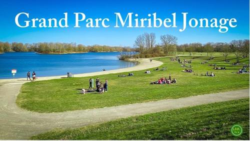 a group of people sitting in a park next to a lake at Casa Papidou, Charmante Maison au calme in Jonage