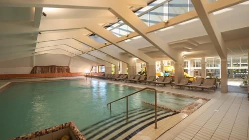 a large indoor pool with chairs in a building at Hotel Terme Jezercica in Donja Stubica