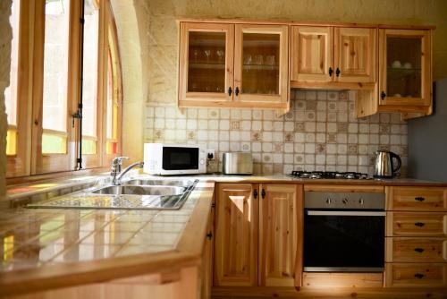 a kitchen with wooden cabinets and a sink and a microwave at Mill House in Għarb