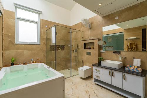 a bathroom with a tub and a glass shower at StayVista at Serenity Farms with Pool, Lawn, Bonfire & BBQ in Sohna