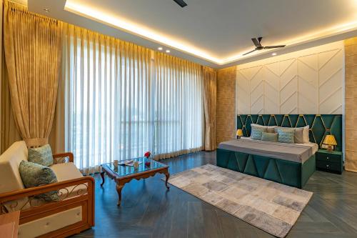 a bedroom with a bed and a couch and a table at StayVista at Serenity Farms with Pool, Lawn, Bonfire & BBQ in Sohna