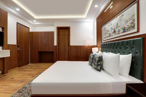 a bedroom with a large white bed with a green headboard at Lemon Tree Hotel, Mcleodganj in McLeod Ganj
