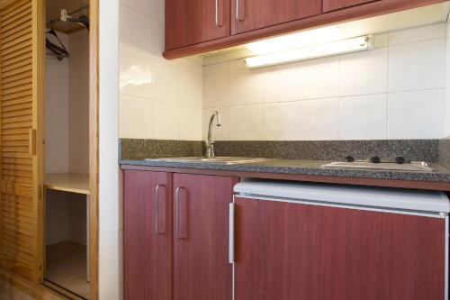 a kitchen with red cabinets and a sink at Apartamentos Casa Maria in San Antonio