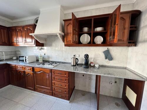 a kitchen with wooden cabinets and a counter top at Braithgate Cosy in Seixal