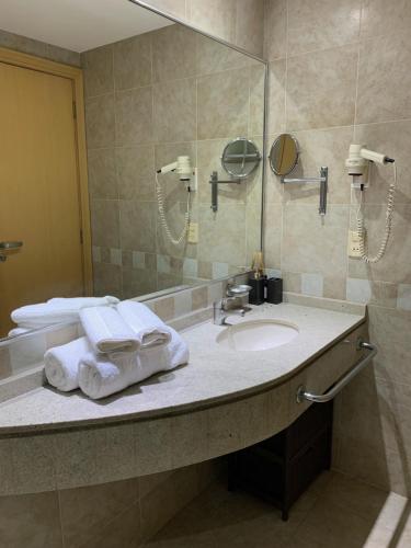 a bathroom with a sink and a mirror and towels at King room - Brooklin flat in Sao Paulo