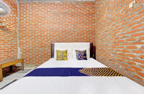 Cette chambre aux murs de briques dispose d'un lit avec deux oreillers. dans l'établissement OYO Life 93010 Omah Bareng Syariah Sambisari, à Kalasan