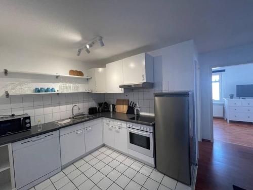 a kitchen with white cabinets and a stainless steel refrigerator at Zentrale Altstadtkoje für bis zu 6 Personen in Neustadt in Holstein