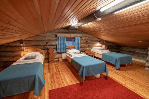 a room with three beds in a log cabin at Fell Centre Kiilopää, Hotelli Niilanpää in Saariselka