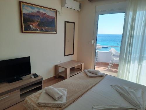 a bedroom with a bed and a television and a balcony at Apartments Val in Dobra Voda