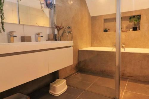 een badkamer met een douche, een wastafel en een bad bij Moderne dubbele benedenwoning met 3 slaapkamers in Rotterdam
