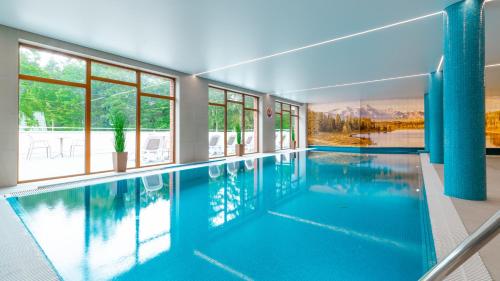a large swimming pool with blue water in a house at Apartamenty z basenem i saunami ROYAL APARTS VIP Stone Hill Centrum in Szklarska Poręba