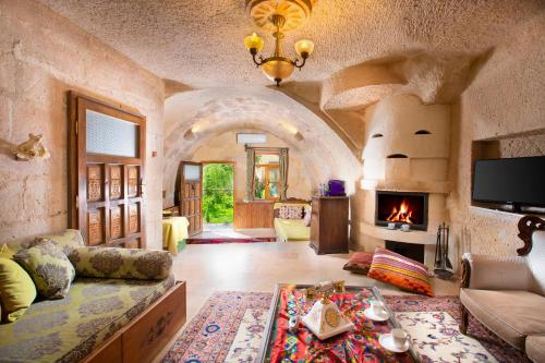 a living room with a couch and a fireplace at Cappadocia Gamirasu Cave Hotel in Ayvalı