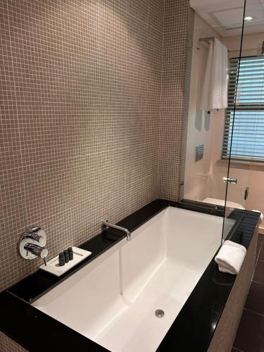 a white bath tub in a bathroom with a window at Mandela Rhodes Place in Cape Town