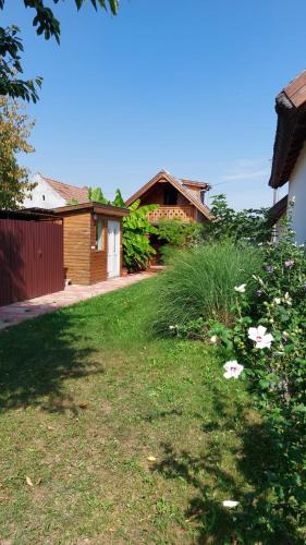 a yard with grass and flowers in front of a house at Újhegy Apartman in Gyarmat