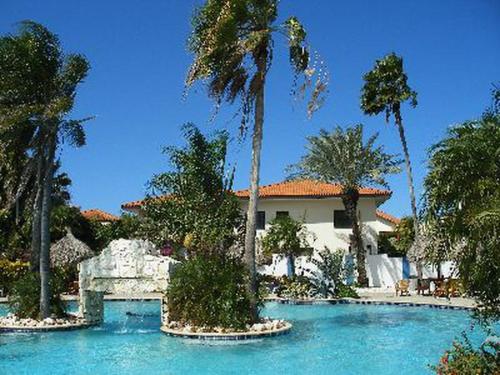 una casa con palmeras y piscina en Club Seru Coral, en Willemstad