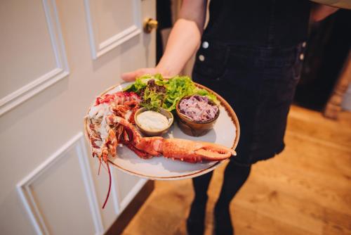 a person holding a plate of seafood and vegetables at The Georgian House in Alderney