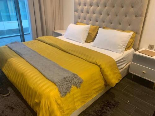 duże łóżko z żółtym kocem i poduszkami w obiekcie Cloud9 Waterfront Luxury Condo w mieście Manama