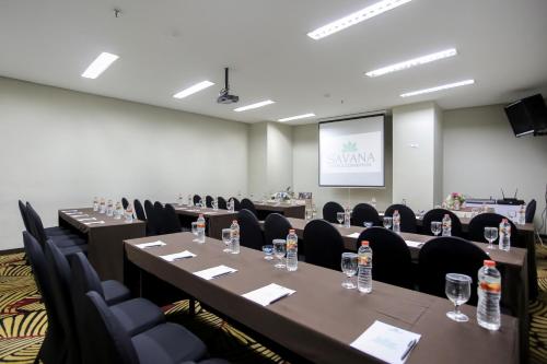 a conference room with tables and chairs and a screen at Savana Hotel & Convention Malang in Malang