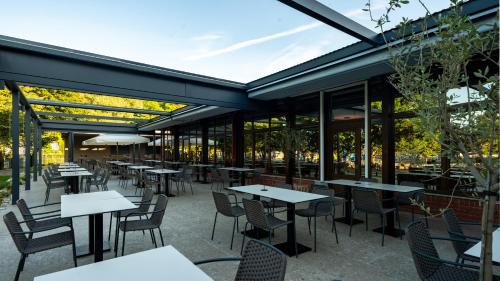 a restaurant with tables and chairs and windows at Hotel Terme Jezercica in Donja Stubica