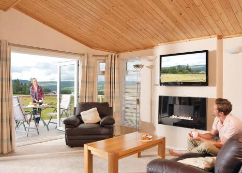 a man and woman sitting in a living room with a tv at Kessock Highland Lodges in North Kessock