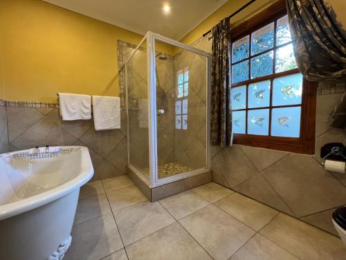 a bathroom with a shower and a tub and a sink at Tillietudlem Nature Reserve in Impendle